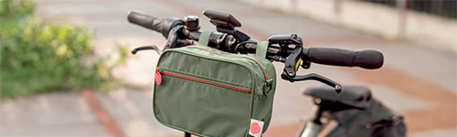 Eine extragroße Gebäckdose in Rot mit weihnachtlichen Motiven wird von einer Person mit grünem Oberteil gehalten