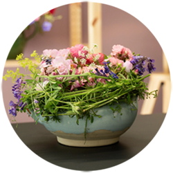 Eine Schale mit einem Rosengesteck steht auf einem dunklen Tisch.