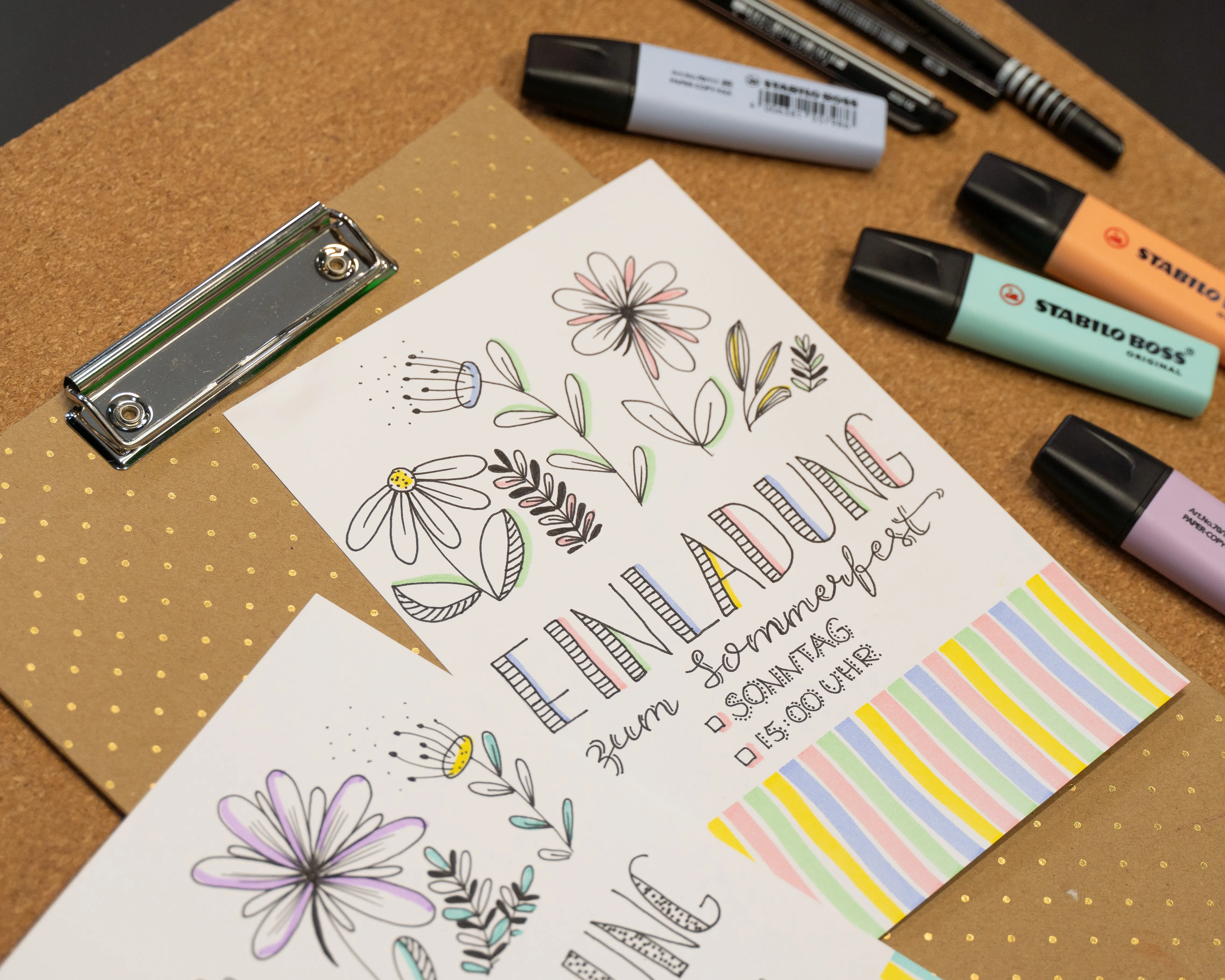 Einladungskarte zum Sommerfest mit handgezeichneten Blumenmotiven und der Aufschrift: "Einladung zum Sommerfest, Sonntag, 18:00 Uhr". Die Karte liegt auf einem gepunkteten Hintergrund, umgeben von Stiften und Textmarkern, Bild verlinkt zum Workshop.